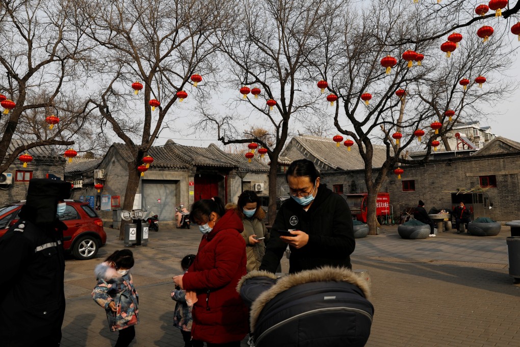 People wearing face masks stand near trees decorated with red lanterns ahead of the Lunar New Year holiday in Beijing. Photo: Reuters