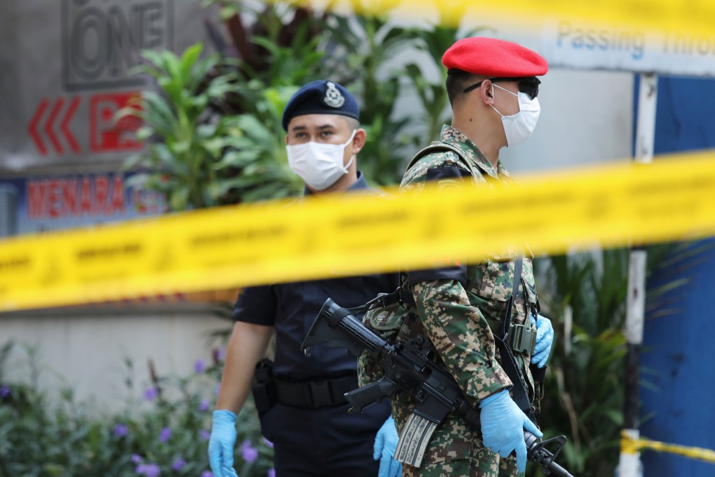 A soldier and police officer stand guard behind police tape in Malaysia. Photo: Reuters