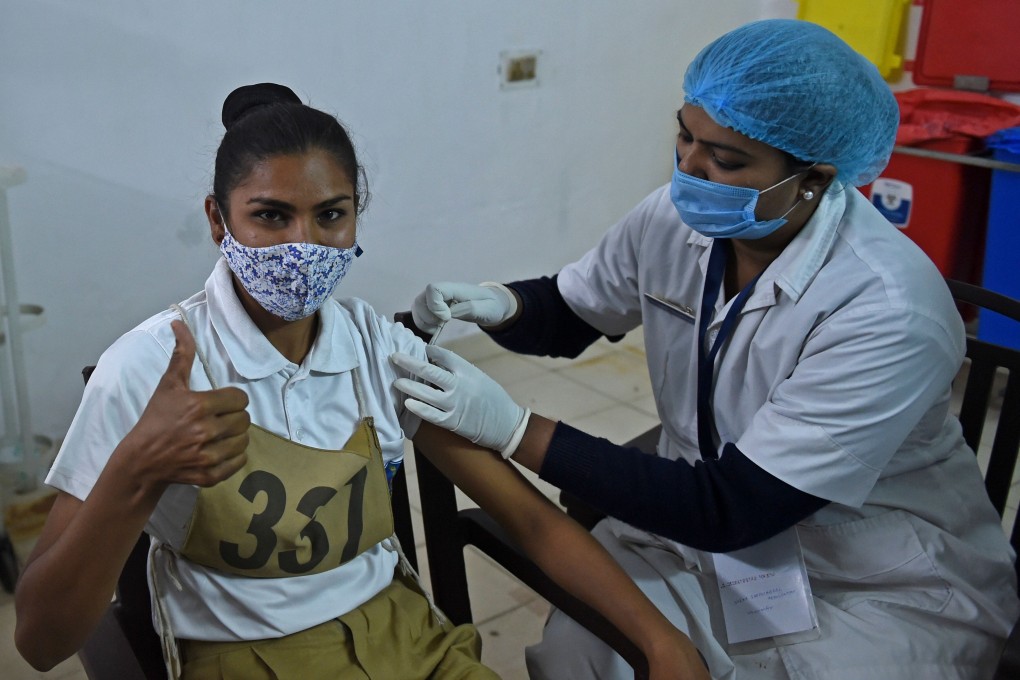A health worker inoculates a policewoman against Covid-19. Photo: AFP
