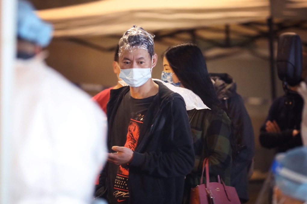 A man halfway through getting his hair dyed lines up for testing in Sham Shui Po during a lockdown on Tuesday. Photo: Handout