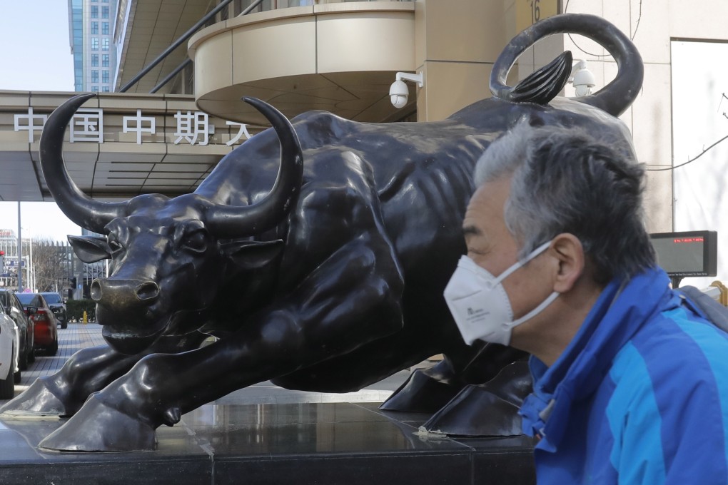 A man wearing walks by a bull sculpture in Beijing in March last year. In Hong Kong, tech stocks faltered on February 4 to end a three-day advance in the Hang Seng Index. Photo: EPA-EFE