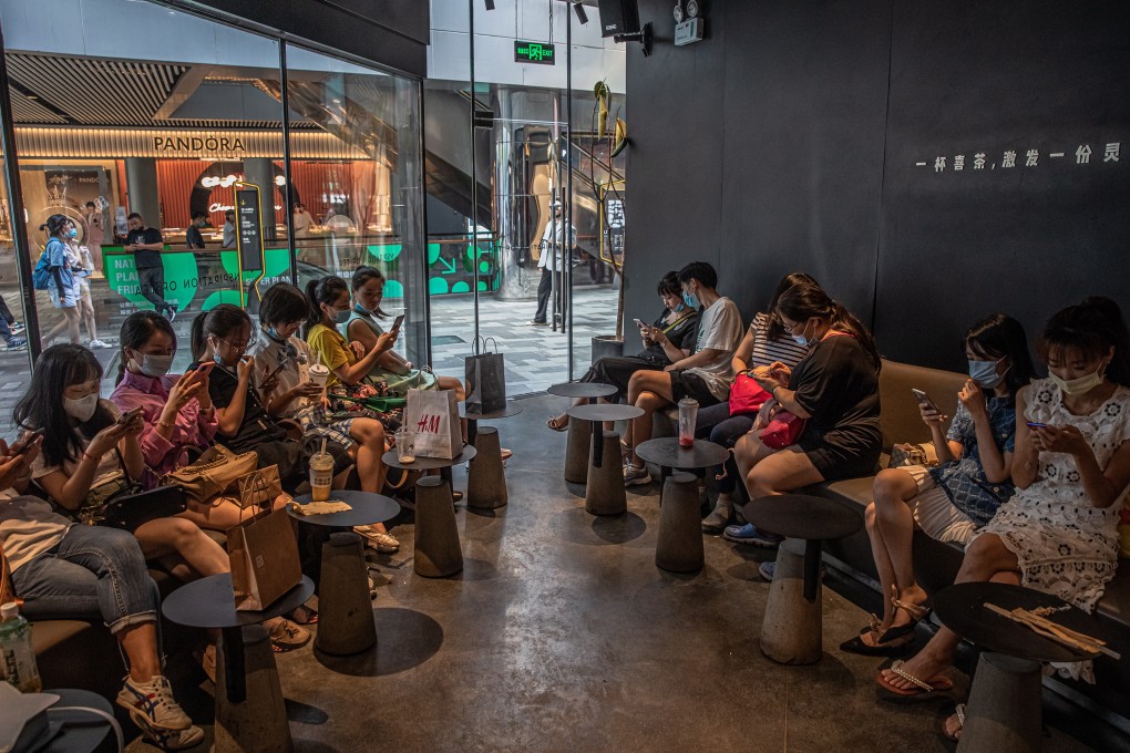 People use their smartphones at a cafe in the shopping area of Sanlitun in Beijing, China on August 7, 2020. Photo: EPA-EFE