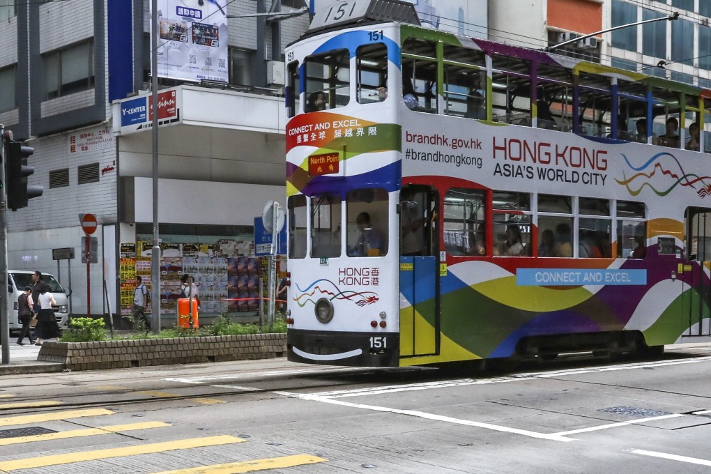 Closed or struggling shops form the backdrop as a tram advertising Hong Kong as “Asia’s World City” stops at a red light in Causeway Bay, one of the city’s major commercial districts. Photo: Nora Tam