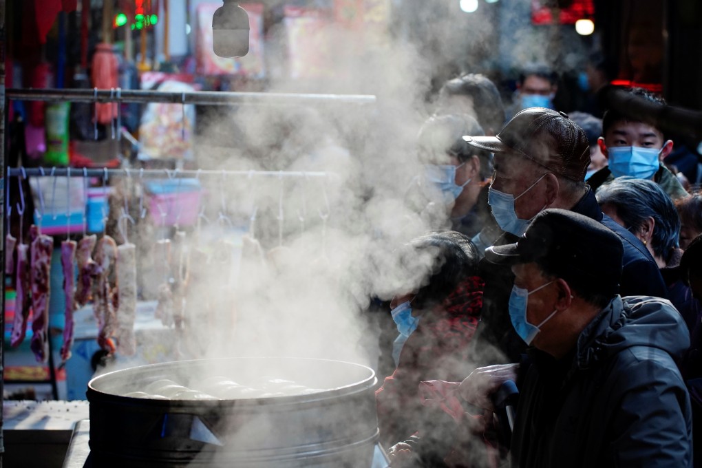 People wearing face masks wait to buy food from a steamed food stall at a street market in Wuhan, Hubei province. Photo: Reuters