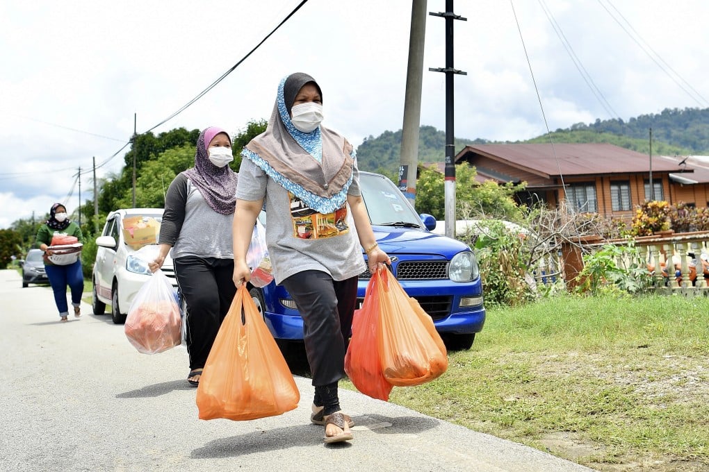 Malaysians carry shopping bags full of supplies as they walk down a deserted road amid the country’s lockdown. Photo: DPA
