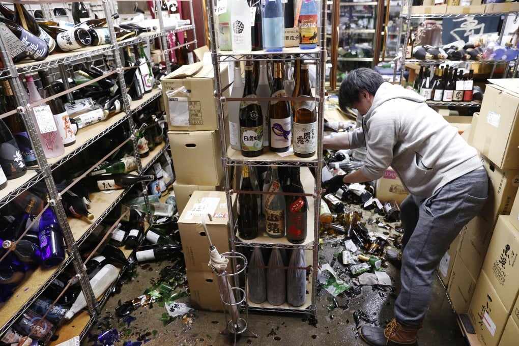 A liquor shop worker clears the damaged bottles following an earthquake in Fukushima on Saturday. Photo: Kyodo News via AP