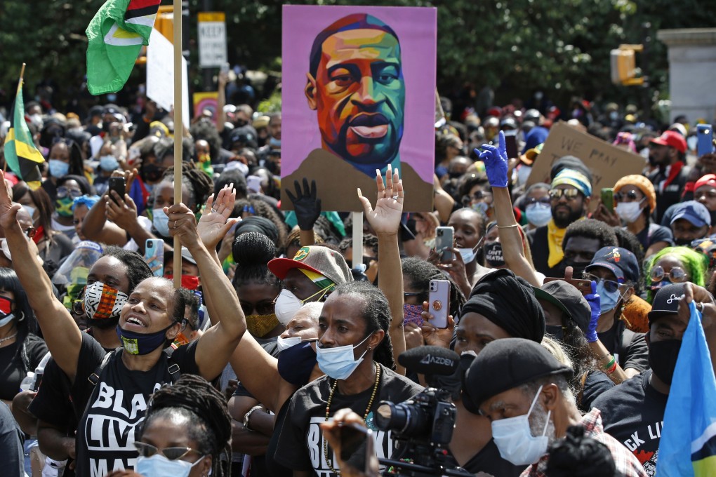 Protesters hold up an image of George Floyd at a Black Lives Matter rally in New York in June. Photo: AP
