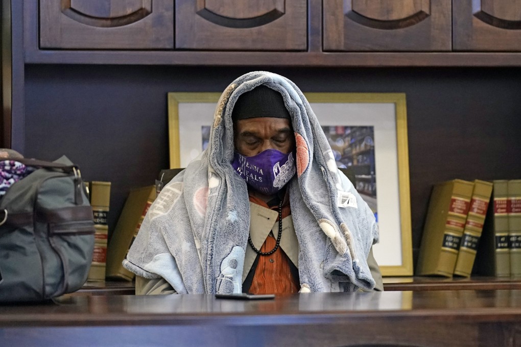 A man tries to stay warm in a furniture store in Houston, which opened as a shelter for those without power. Photo: AP