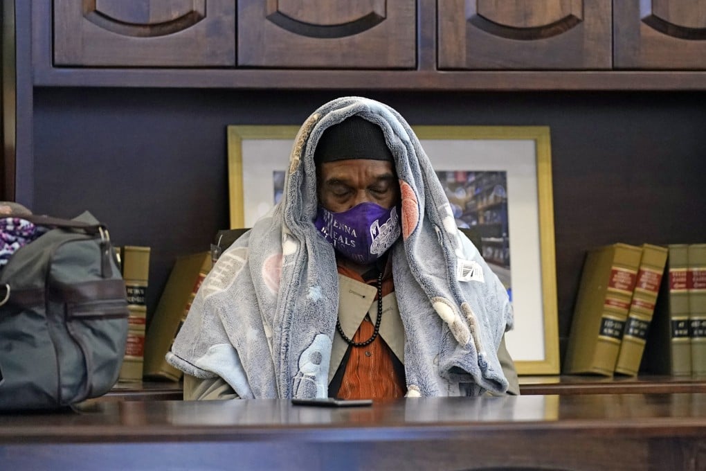 A man tries to stay warm in a furniture store in Houston, which opened as a shelter for those without power. Photo: AP