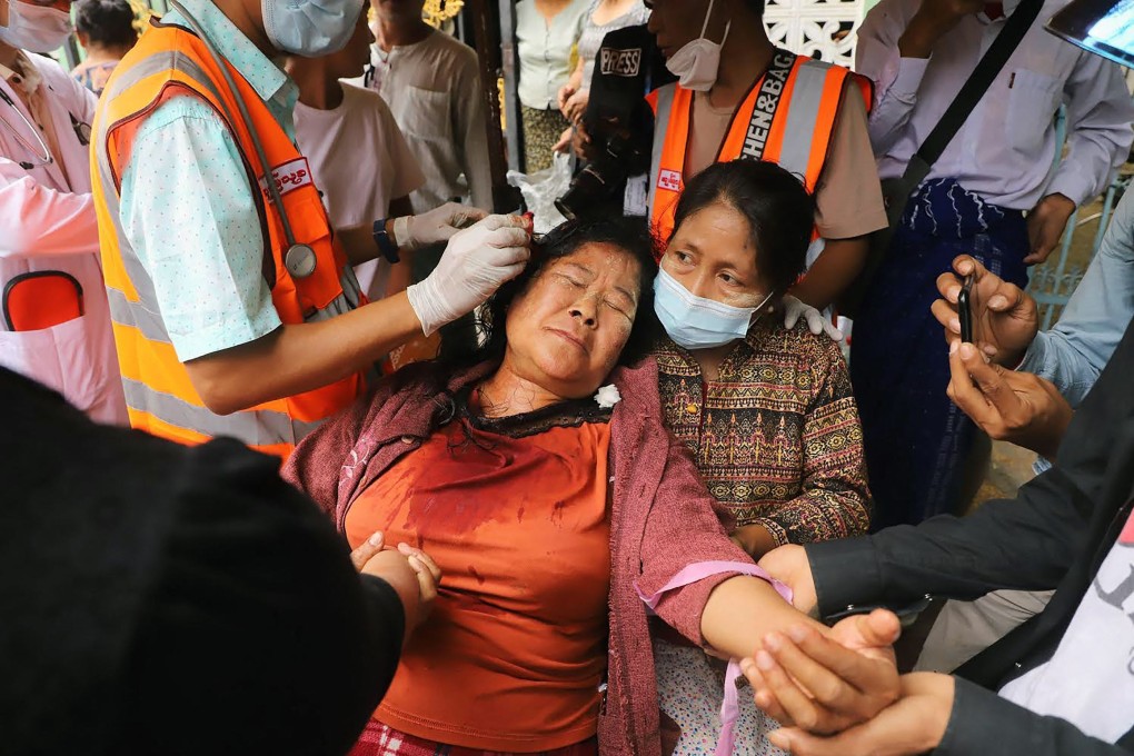 A protester has a wound on her head treated after being beaten by security forces during a demonstration against the military coup in Mandalay, Myanmar on Saturday. Photo: AFP