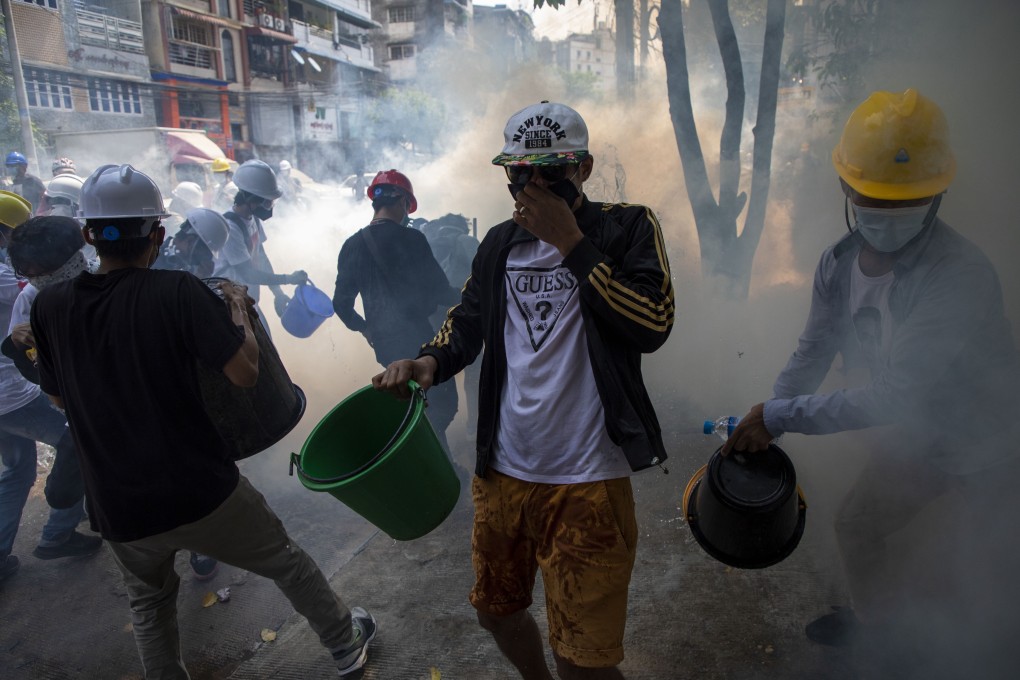 Protesters try to extinguish tear gas canisters during a demonstration against the military coup and detention of civilian leaders in Myanmar. Photo: DPA
