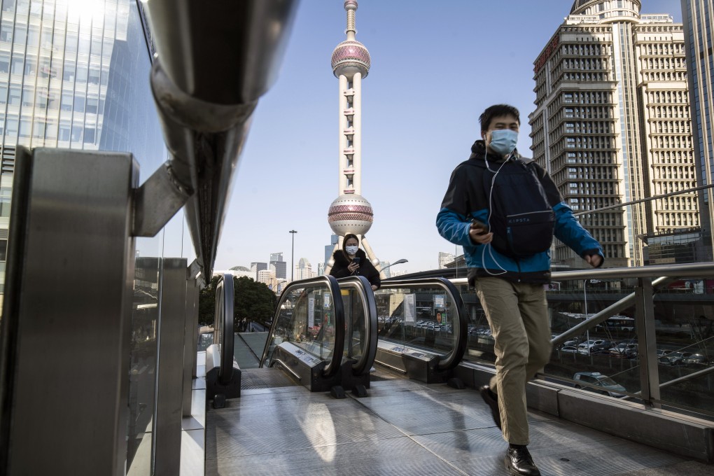 Pedestrians wearing protective masks ride on an escalator in Pudong's Lujiazui Financial District in Shanghai. Investors are looking to the “Two Sessions” in Beijing later this week for signs of further policy support: Photo: Bloomberg.