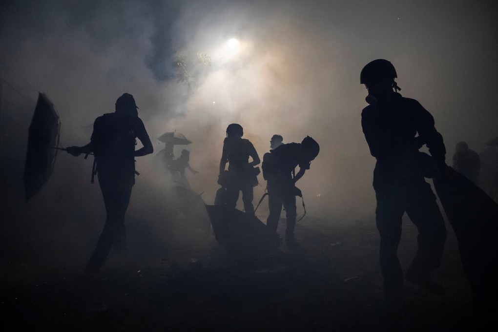 Anti-government protesters stand in a cloud of tear gas unleashed during a stand off with riot police at the Chinese University of Hong Kong on November 12, 2019. Photo: Reuters