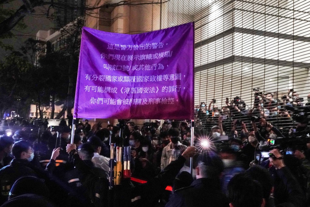 Police officers raise a flag warning supporters of the 47 pro-democracy activists charged with subversion outside West Kowloon Magistrates’ Courts in Hong Kong on Thursday, March 4. Photo: Felix Wong