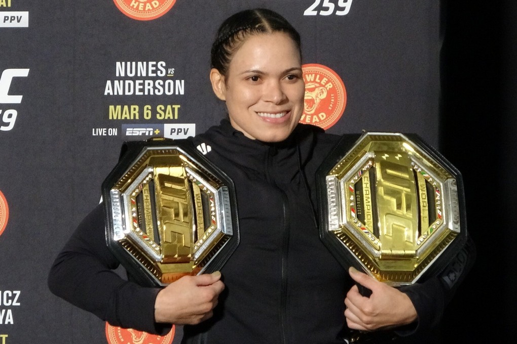 Amanda Nunes poses with her two titles after UFC 259. Photo: Drake Riggs