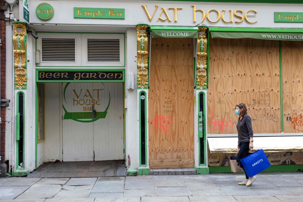 A woman walks past a boarded up bar in Dublin in October last year. Photo: AFP