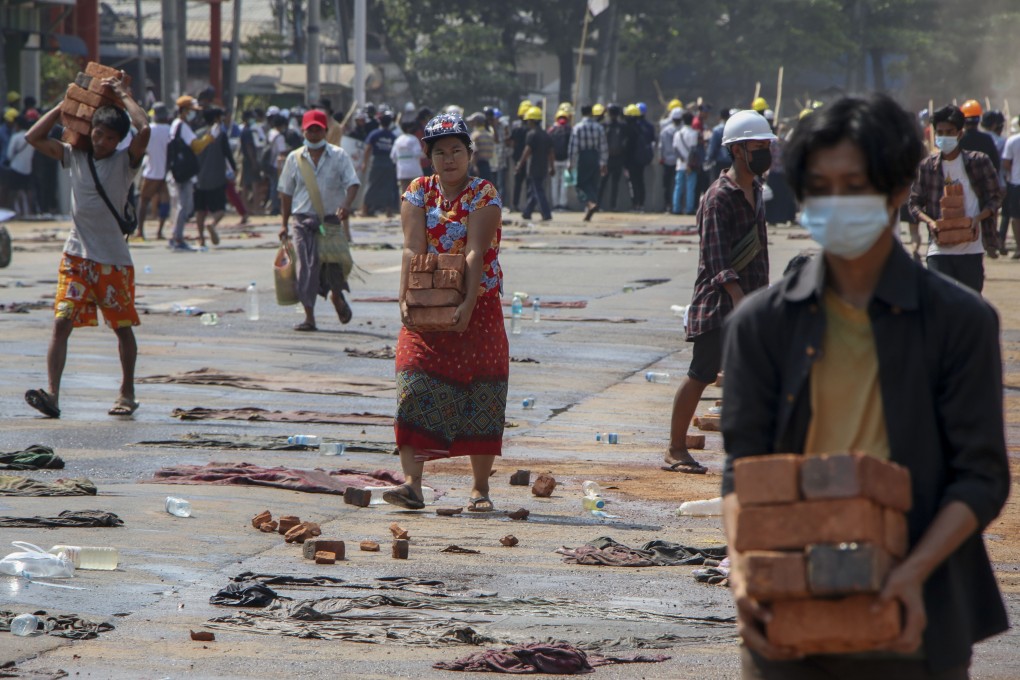 People carry bricks to help anti-coup protesters to build makeshift barricades in Yangon on Thursday. Photo: AP