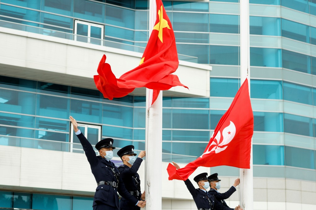 Police officers gesture next to Chinese and Hong Kong flags at a flag-raising ceremony at Golden Bauhinia Square in the financial capital. Photo: Reuters