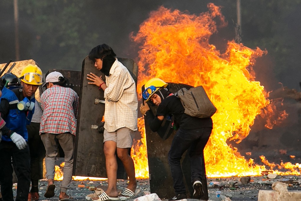 Protesters take cover behind home-made shields as they confront the police during a crackdown on demonstrations against the military coup in Yangon, Myanmar. Photo: AFP