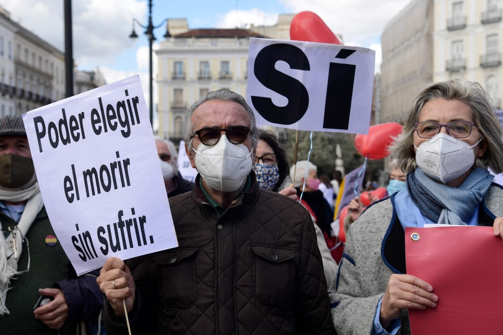 A man in Madrid holds a placard reading ‘To choose to die without suffering’ during a demonstration in support of a law legalising euthanasia. Photo: AFP
