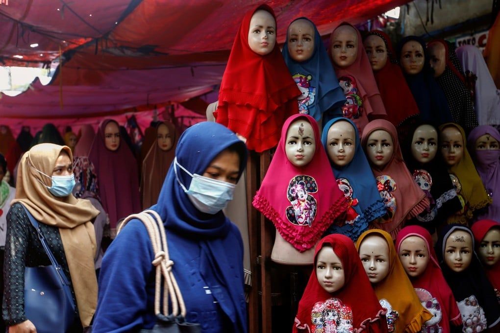Women walk past hijabs for sale at the Tanah Abang textile market in Jakarta, Indonesia, on Tuesday. Photo: Reuters