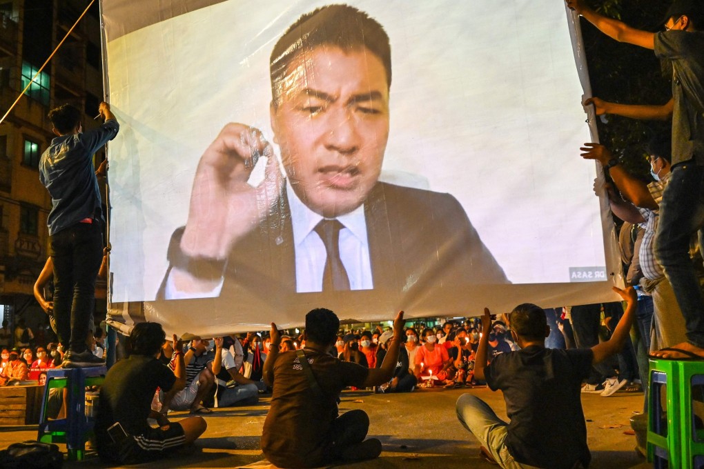 Protesters watch as a video featuring Dr Sasa is projected on a screen during an anti-coup demonstration in Yangon. Photo: AFP