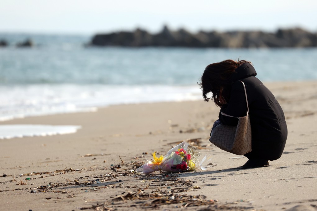 A woman prays and offers flowers for the victims of the devastating 2011 earthquake and tsunami in Sendai, Miyagi prefecture, on March 11, 2021. Photo: EPA-EFE/Jiji Press