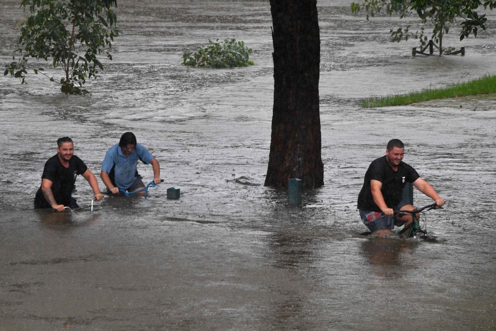 People ride bicycles through a flooded park in Penrith, Sydney. Photo: AFP