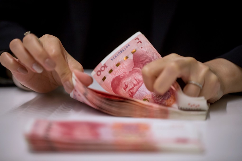 A bank employee counts Chinese one-hundred yuan banknotes. The reorganisation of Peking University Founder Group will involve up to US$11.3 billion. Photo: Bloomberg