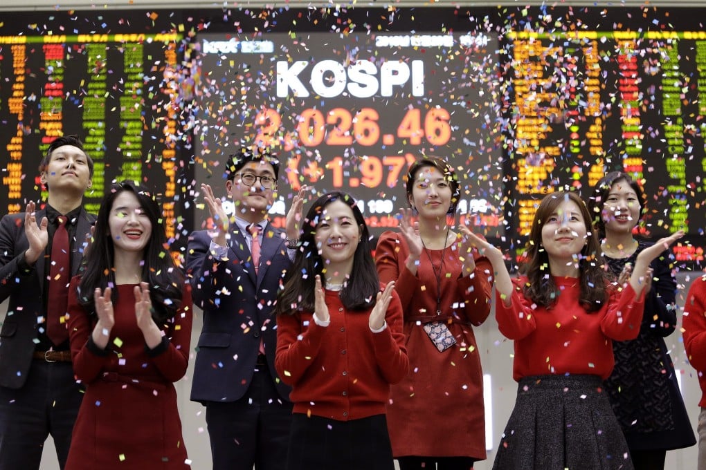 Staff members of the Korea Exchange applaud as they throw confetti for the media during the year's market closing ceremony near a screen showing the Korea Composite Stock Price Index (KOSPI) at the Korea Exchange in Seoul on Thursday, December 29, 2016. Photo: AP