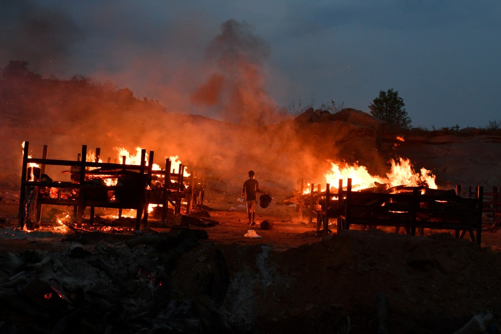 A volunteer walks between burning pyres of dead bodies at a crematorium near Bangalore. Photo: Reuters