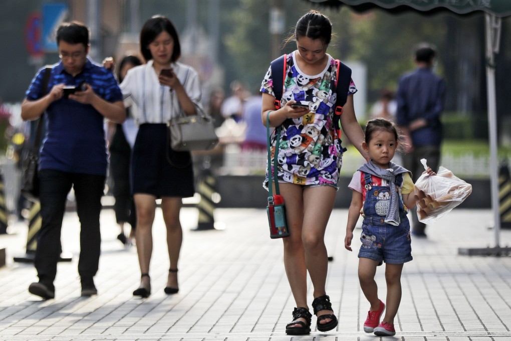 Pedestrians view their smartphones as they walk along a street in Beijing. Photo: AP