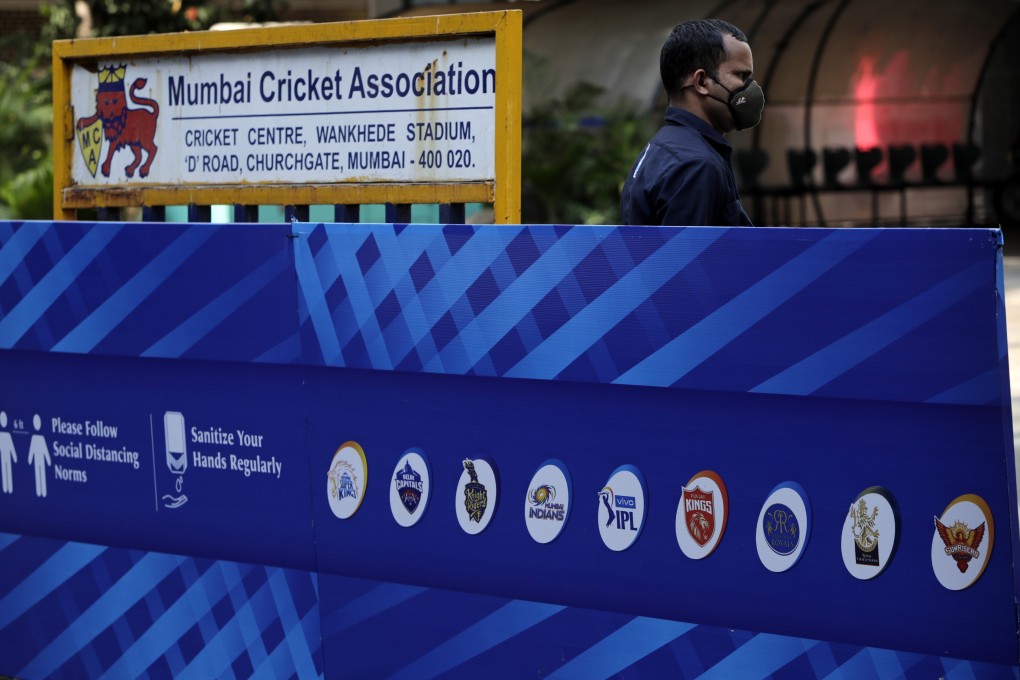 A security guard wearing a face mask stands next to a hoarding of teams taking part in the Indian Premier League 2021 season, outside Wankhede Stadium in Mumbai. Photo: AP