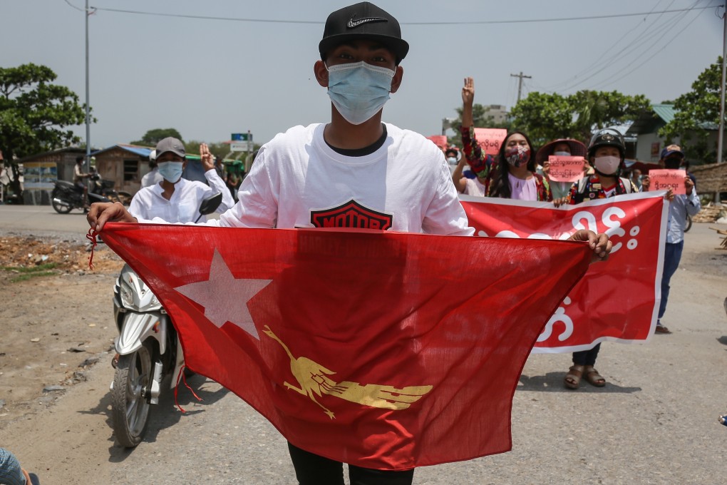 A demonstrator carries a National League for Democracy flag during a rally in Mandalay. Photo: EPA
