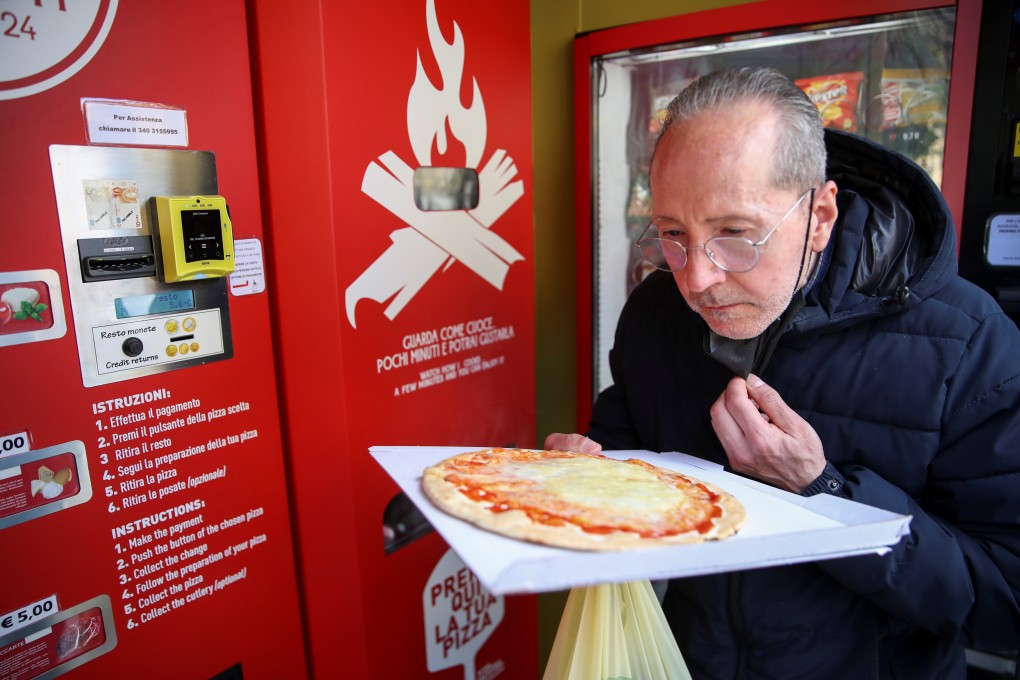 Customer Claudio Zampiga sniffs his pizza at the first automatic pizza vending machine in Rome, Italy on Thursday. Photo: Reuters