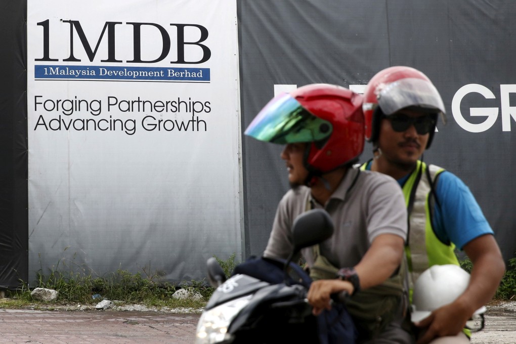 Motorcyclists pass a 1MDB hoarding at the Tun Razak Exchange development in Kuala Lumpur, Malaysia. Photo: Reuters