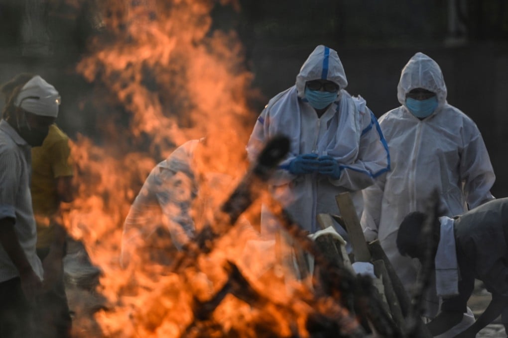 Relatives wearing protective gear perform rituals at a crematorium in New Delhi on Tuesday as they prepare to cremate a loved one who died of Covid-19. Photo: AFP