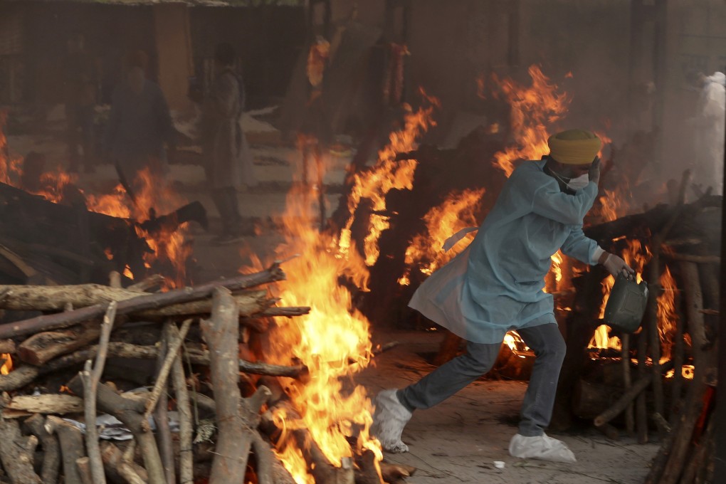 A crematorium volunteer runs to avoid the heat emitted from the burning funeral pyres of Covid-19 victims in Jammu, India, on Wednesday. Photo: AP