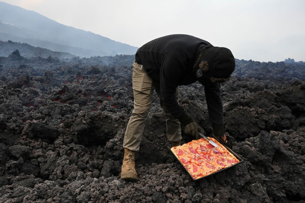 David Garcia places a pizza on a lava river that comes down from the Pacaya volcano at the Cerro Chino hill in San Vicente Pacaya municipality, Guatemala on Wednesday. Photo: AFP