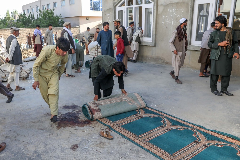 Afghan men collect bloodstained prayer mats at the scene of an attack that targeted a mosque on the outskirts of Kabul, Afghanistan on Friday. Photo: EPA-EFE