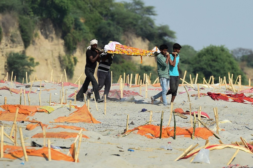 People carry a body past shallow graves on the banks of the Ganges River. Photo: AFP
