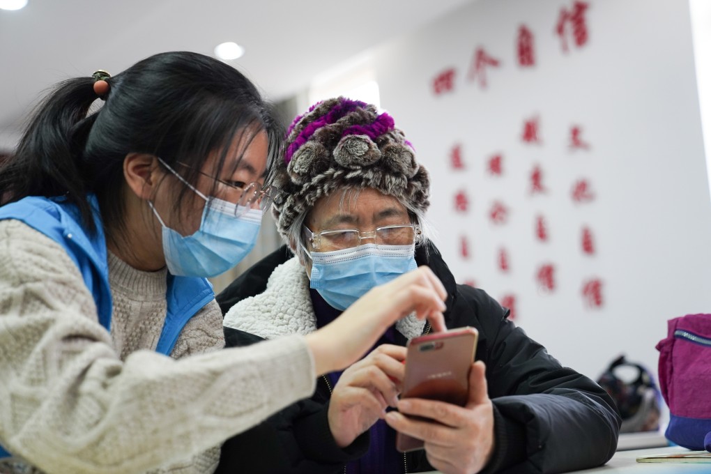 A student volunteer from Beijing Foreign Studies University teaches as a senior resident learns how to use a health-tracking app, introduced amid the COVID-19 outbreak. Photo: Xinhua