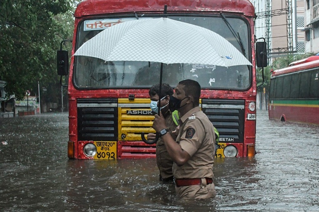 A policeman helps a public transport driver to cross a flooded street in Mumbai. Photo: ZUMA Wire/dpa