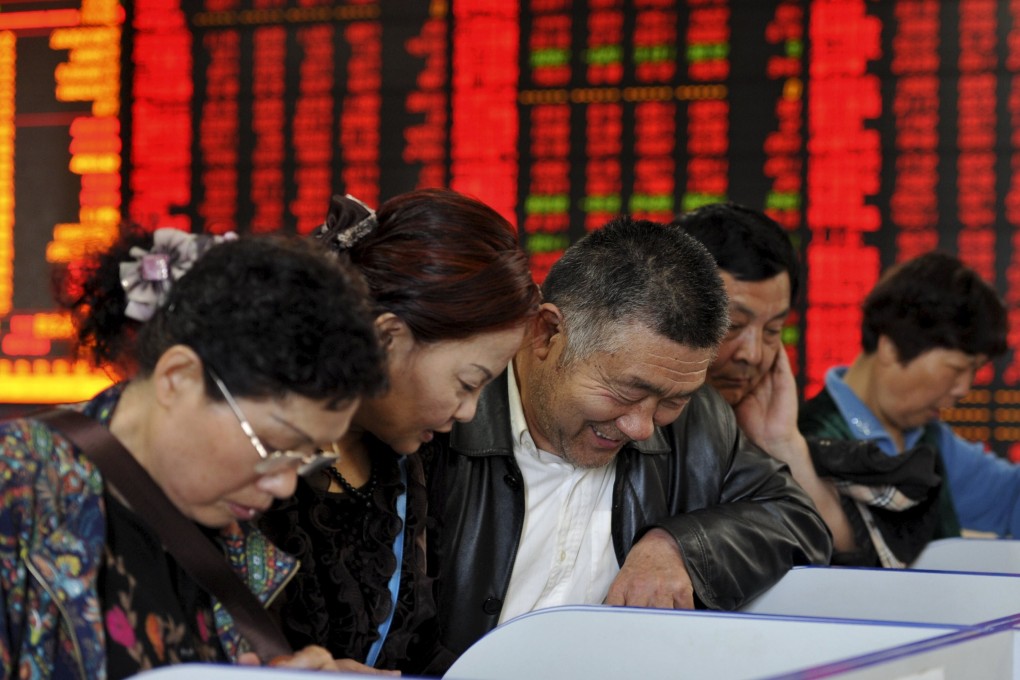 Investors look at computer screens in front of an electronic board showing stock information at a brokerage house in Fuyang, Anhui province. Photo: Reuters