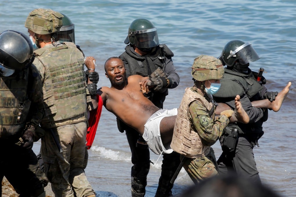 A Moroccan citizen is carried by Spanish soldiers and riot police at El Tarajal beach, near the fence at the Spanish-Moroccan border, on Tuesday. Photo: Reuters