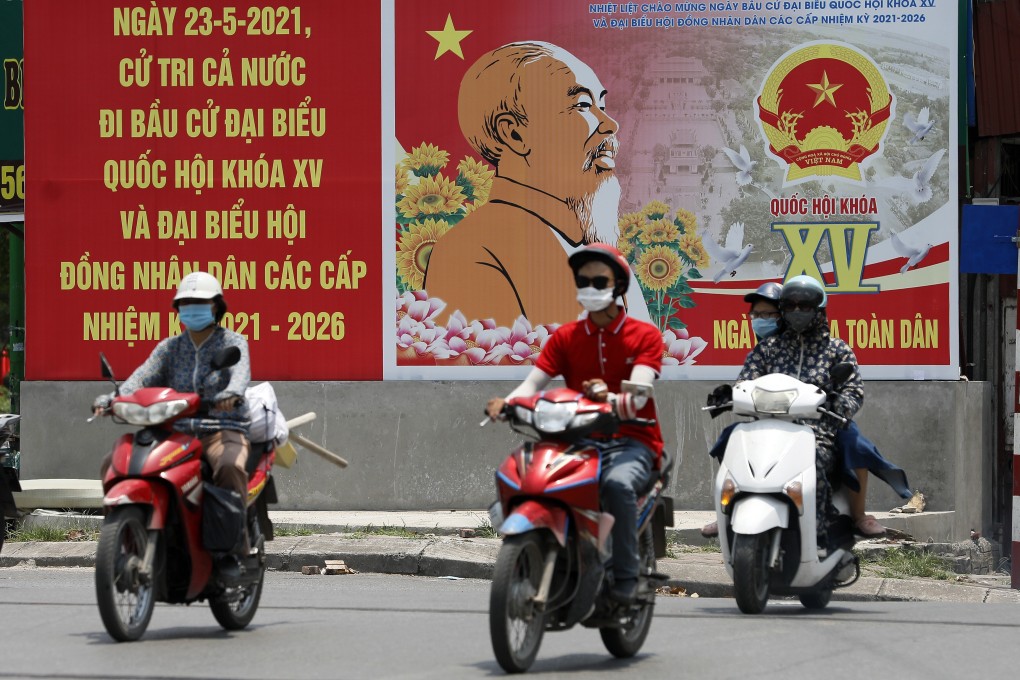 People ride motorbikes past a poster featuring information on coming legislative elections in Hanoi, Vietnam, on Wednesday. Photo: EPA