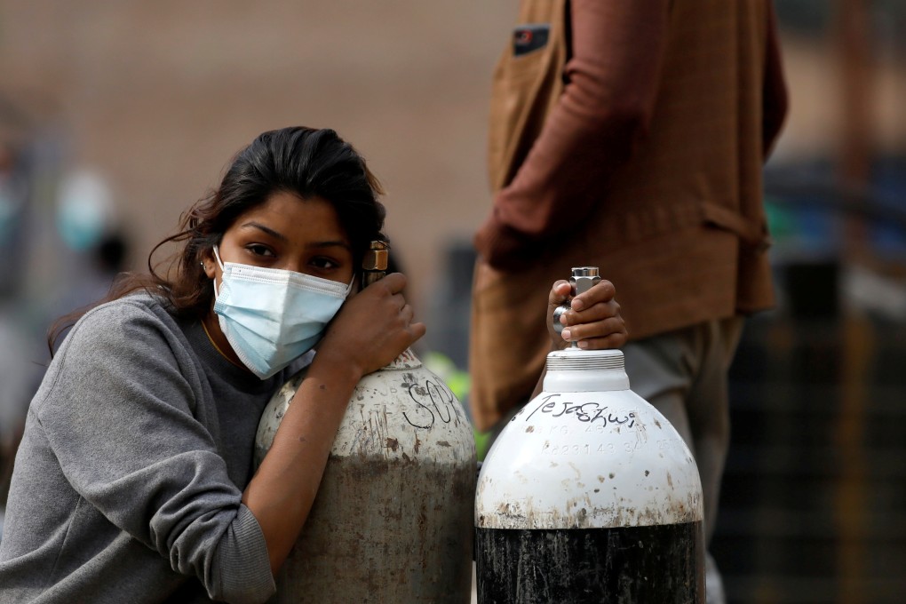 A woman in Kathmandu, Nepal, holds on to much-needed oxygen cylinders for a Covid-19 patient after refilling them at a factory. Photo: Reuters