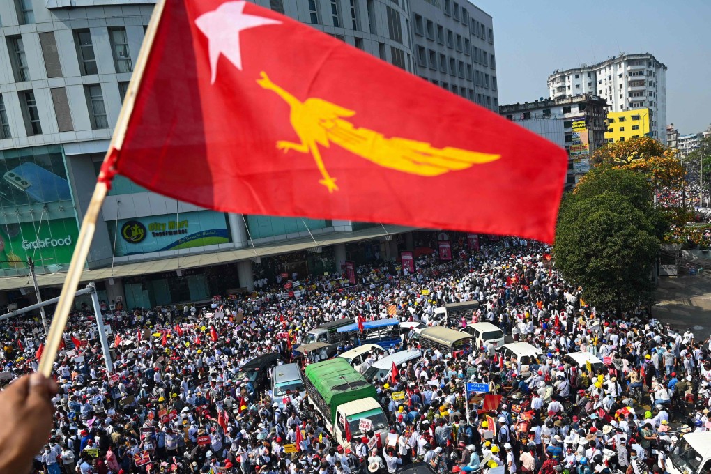 A protester waves the National League for Democracy flag while others take part in a demonstration against the military coup in Yangon. Photo: AFP