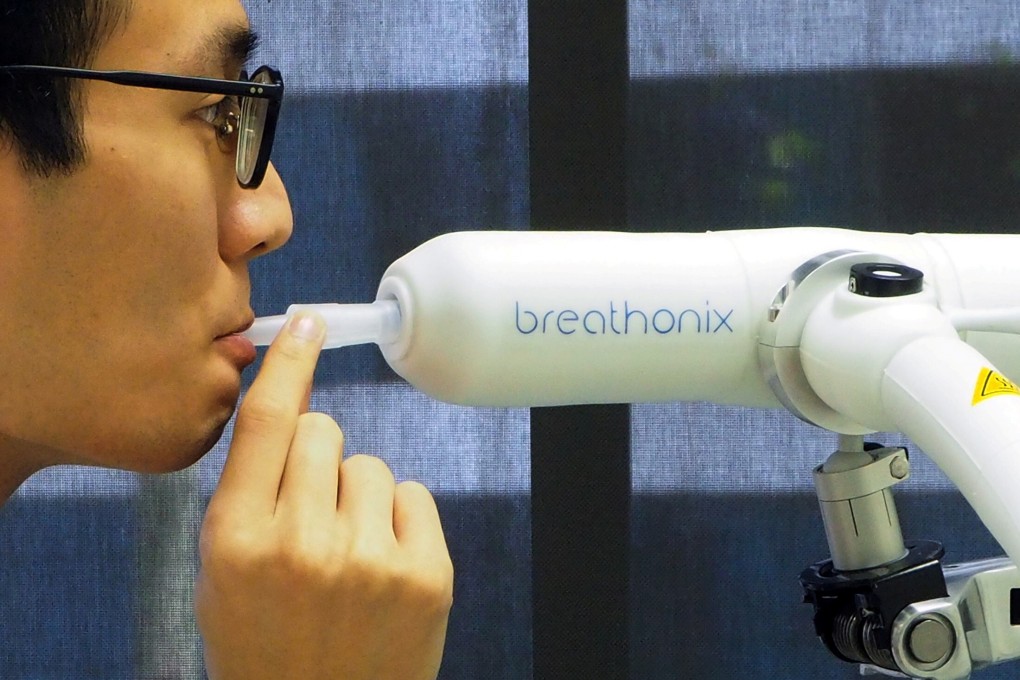 A staff member demonstrates the Breathonix breathalyser test kit. Photo: Reuters