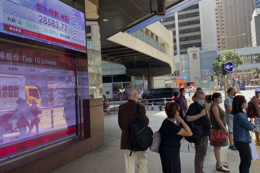 People walk past a bank's electronic board showing the Hang Seng Index at Hong Kong Stock Exchange near Central. Photo: AP
